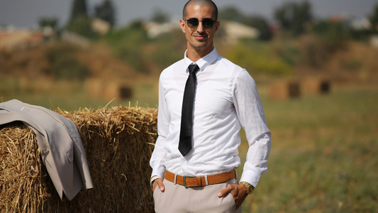 A model in a Saint Valence classic dress shirt and wrap, set against a warm, autumnal backdrop with fallen leaves, showcasing confidence and elegance.