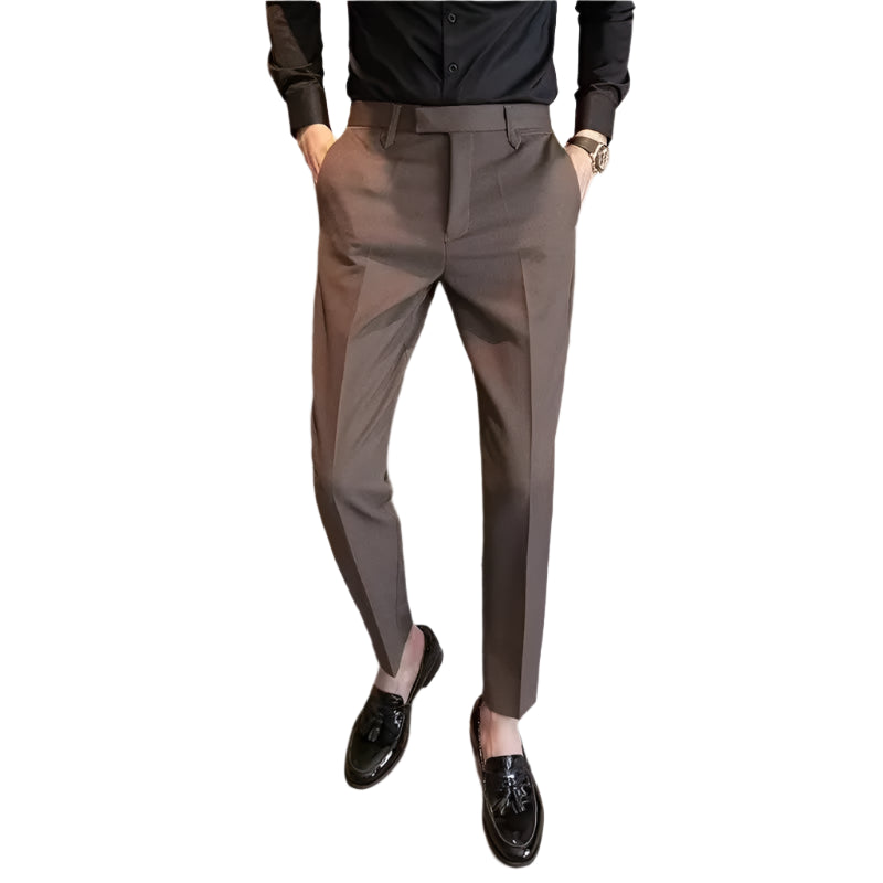 Person wearing brown dress pants and black shoes standing in front of a wooden cabinet.