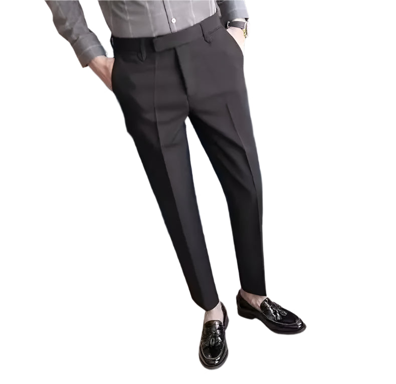 Person wearing dark gray pants and black shoes in a room with a blue chair and table.