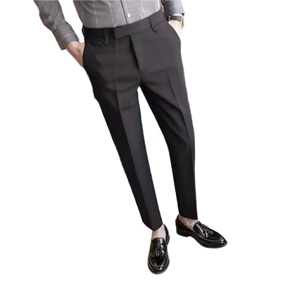 Person wearing dark gray pants and black shoes in a room with a blue chair and table.